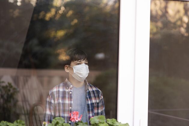 健康戴着口罩的男孩在看户外流行预防青少年