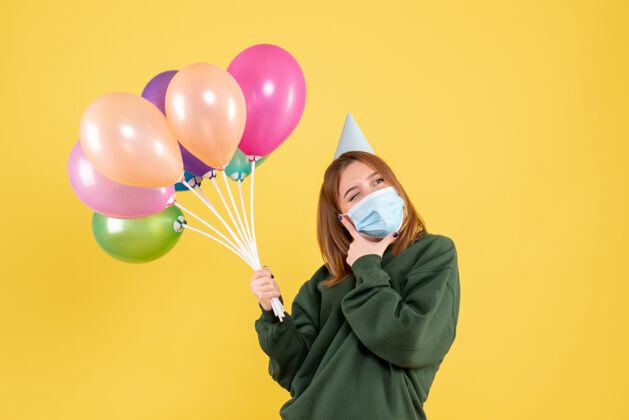欢乐正面图：手持彩色气球的年轻女性女性病毒年轻女性