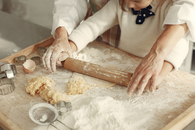 烹饪厨房里的人奶奶带着小女儿成年妇女教小女孩做饭烘焙成人乐趣