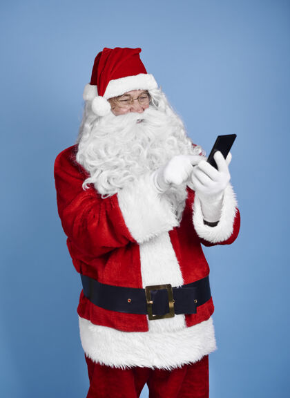 打字圣诞老人用手机在摄影棚拍摄短信电话信息