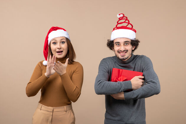 圣诞老人新年气氛喜庆概念搞笑快乐可爱的情侣戴着灰色的红色圣诞老人帽男人大人帽子
