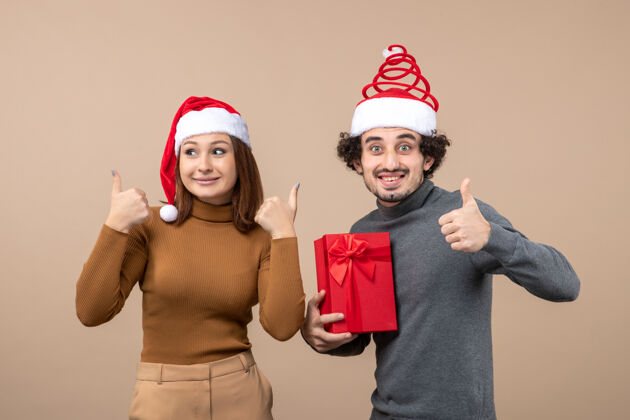 圣诞节新年气氛喜庆的概念与搞笑幸福可爱的情侣戴着红色圣诞老人帽完美的姿态在灰色圣诞老人男人泳帽
