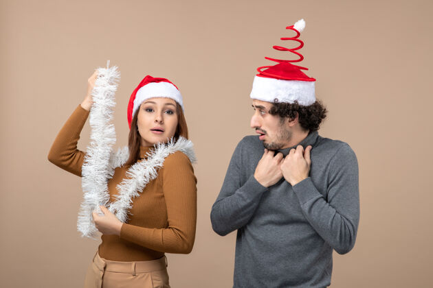 兴奋新年气氛喜庆的概念与兴奋酷满意的可爱情侣戴着红色圣诞老人帽的灰色镜头心情男性圣诞老人