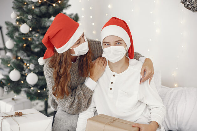 人为圣诞节做准备的人冠状病毒主题妈妈和儿子玩穿白毛衣的男孩病毒家传统