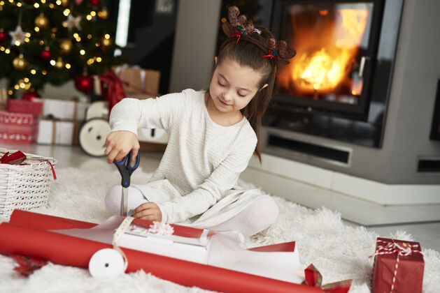 包装小女孩在打包圣诞礼物家居室内坐地毯