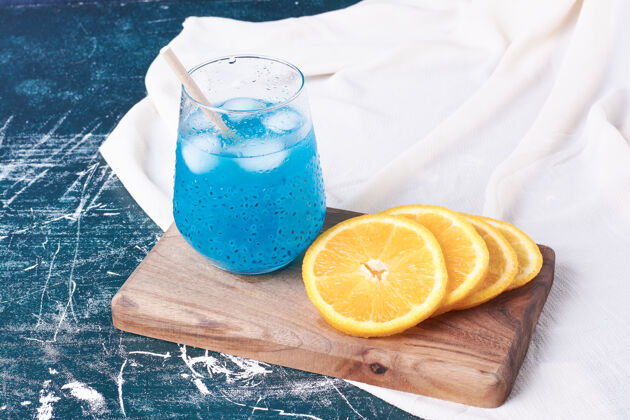 质量橘子和一杯饮料放在蓝色上木制光生物