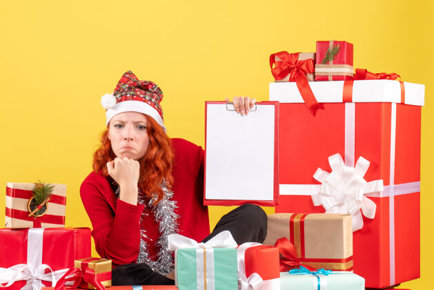 前面年轻女子围坐在黄色墙壁上的不同圣诞礼物前视图盒子节日年轻