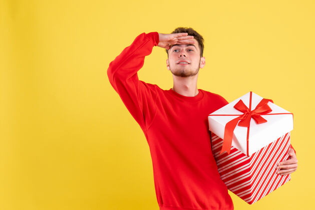 红色正面图穿红衬衫的年轻男子拿着圣诞礼物遥望远方距离衬衫年轻
