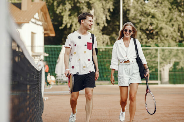 年轻网球场上的一对年轻夫妇两个穿着运动服的网球运动员女孩活动运动装