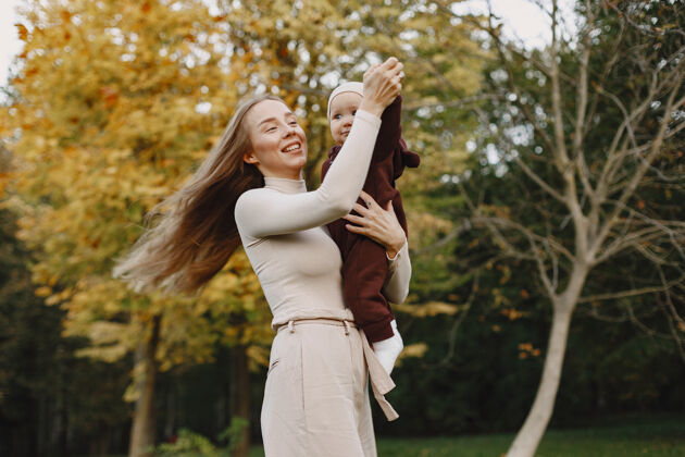 年轻时尚妈妈带着女儿人们走在外面穿着棕色毛衣的女人自然快乐父母