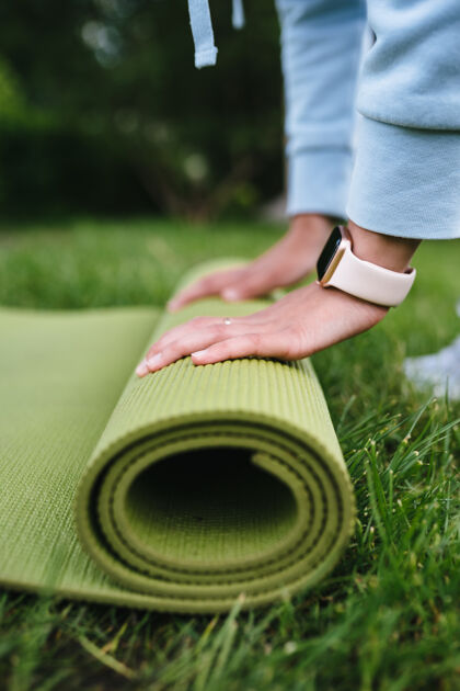 体操妇女折叠卷健身特写后 在公园锻炼滚动垫子健康