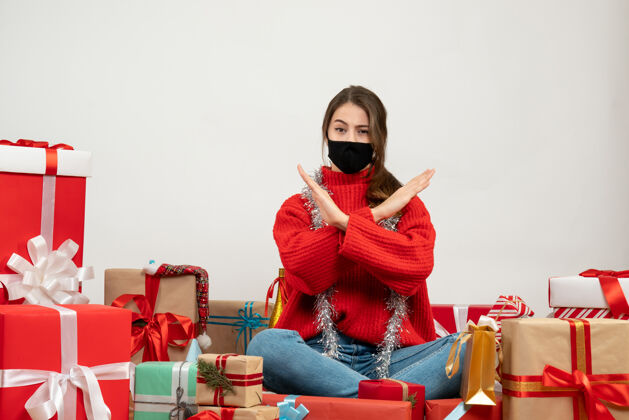 礼物手交叉着红毛衣的年轻女孩围坐在礼物旁边 白色的面具是黑色的女孩周围年轻女孩