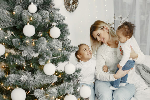 亮光人们在为圣诞节做准备母亲在和女儿们玩耍一家人在节日的房间里休息孩子穿着毛衣给毛衣女儿