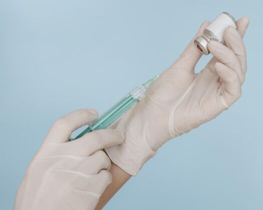 治疗双手戴着手套拿着装有疫苗瓶的注射器补救安全免疫