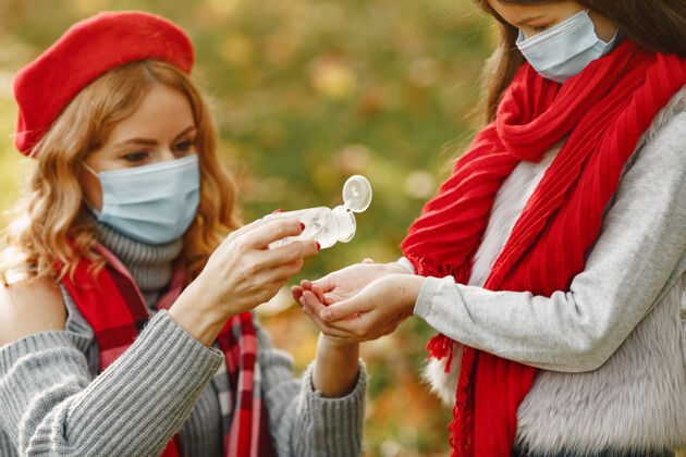 红色秋天公园里的一家人冠状病毒主题母亲带女儿人们用杀菌剂女人树叶人