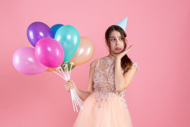 快乐戴着派对帽的悲伤女孩拿着粉红色的气球悲伤气球公主