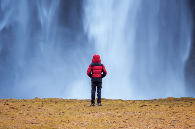 站立冰岛的塞尔加兰兹瀑布穿红色夹克的家伙看着塞尔加兰兹瀑布前面环境冰岛