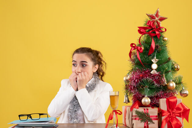 新郎前视图女医生围坐在圣诞礼物和黄色背景上的树害怕快乐害怕礼物