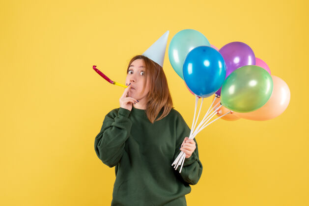多彩正面图是一位年轻的女士 手里拿着五颜六色的气球聚会年轻的女人桌子