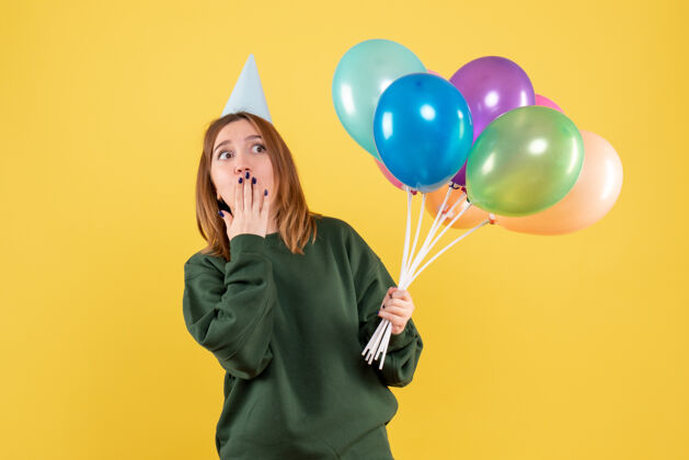 庆祝正面图是一位年轻的女士 手里拿着五颜六色的气球颜色吹年轻的女人