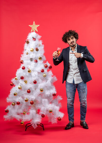 圣诞有胡子的年轻人点着酒 站在装饰好的白色圣诞树旁庆祝新年站着男人年轻人