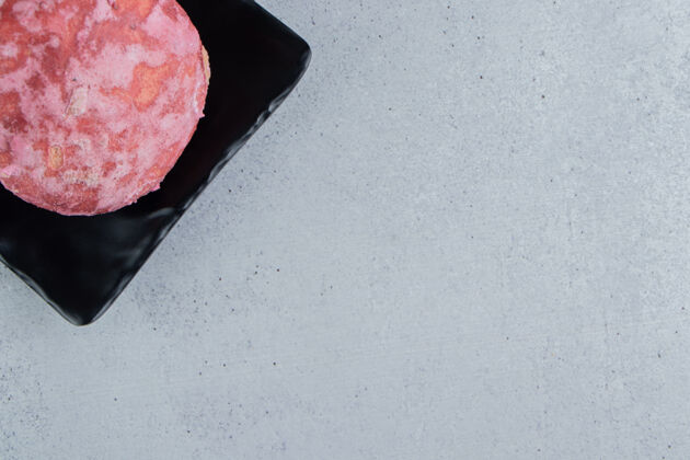糕点一个美味的粉红色饼干放在大理石背景的黑色盘子里甜点美味美味