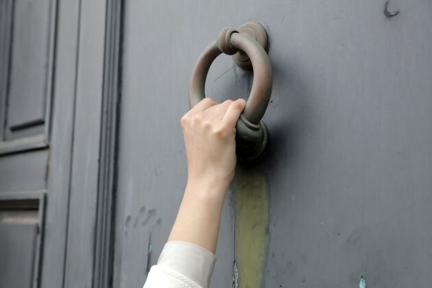 入口一个人用一个旧门环敲门的特写镜头门棕色建筑