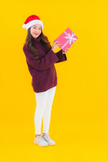 庆祝肖像美丽的亚洲年轻女子穿圣诞装饰主题钱手手势