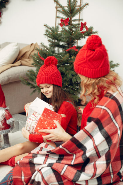 给人们在为圣诞节做准备母亲在和女儿玩耍一家人在节日的房间里休息孩子穿着红色毛衣母亲杉木室内