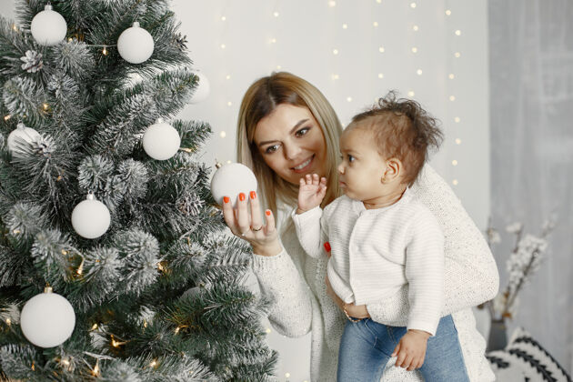 光泽人们在为圣诞节做准备母亲在和女儿玩耍一家人在节日的房间里休息孩子穿着毛衣国际肖像光泽