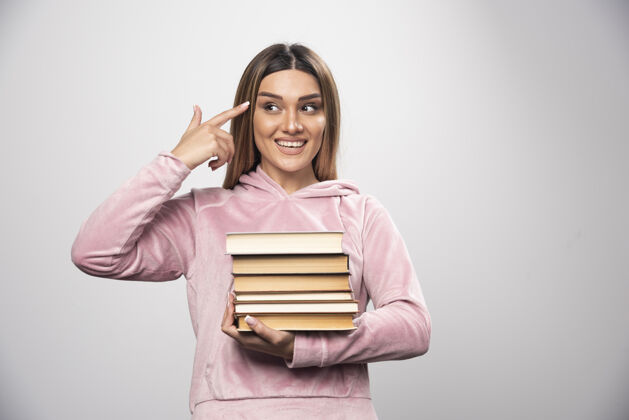 学生穿着粉色运动衫的女孩手里拿着一堆书 感觉很聪明教育粉色成人