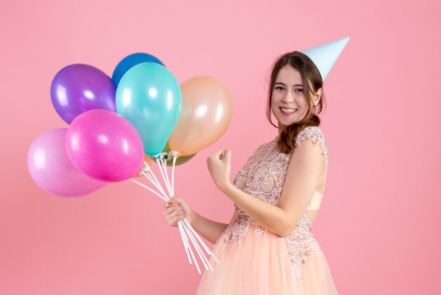 粉色快乐的派对女孩 戴着派对帽 手里拿着粉色的气球帽子快乐人