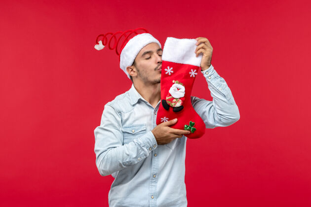 表情年轻人亲吻红墙圣诞袜的正面图吉祥物接吻男性