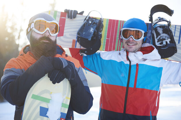 雪两个男子滑雪板运动员的腰向上山抬高聚会