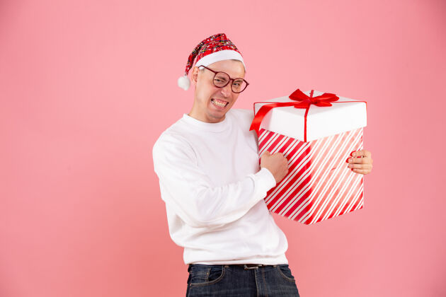 礼物一个年轻人拿着大礼物在粉红色墙上的前视图盒子前面人
