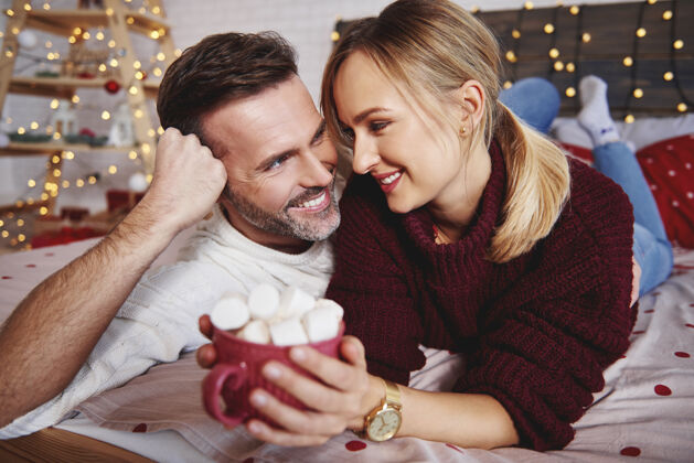 热巧克力微笑的男人在圣诞节拥抱他的女朋友饮料热身圣诞装饰品