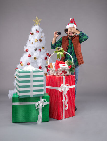圣诞树年轻的男性在灰色的节日礼物帽子礼物时尚