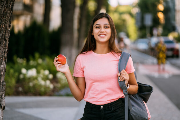 美丽一个拿着苹果的年轻女子的画像 背景是街道健康苹果年轻