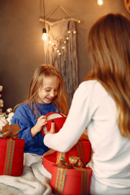 一起人们在为圣诞节做准备母亲在和女儿玩耍一家人在节日的房间里休息孩子穿着蓝色毛衣毛衣礼物圣诞