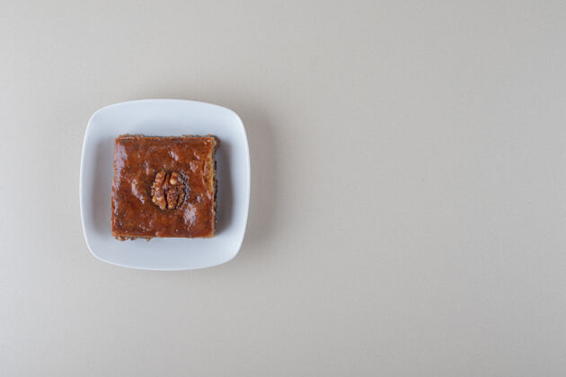糖在大理石背景上的盘子上放着一个小bakhlava烘焙食品商品甜点
