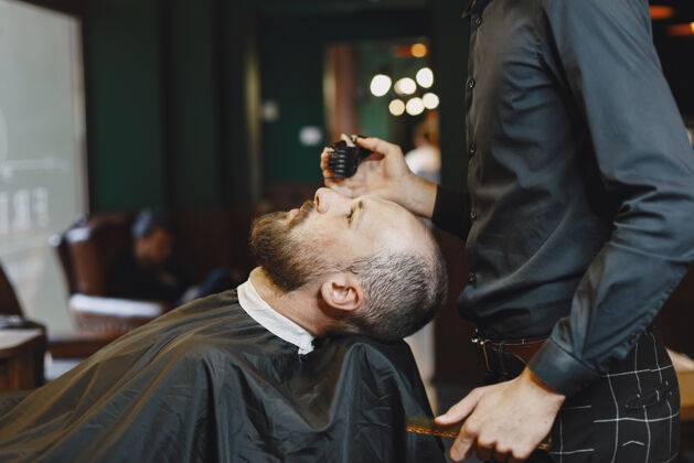 服务有胡子的男人有客户的理发师有梳子和剪刀的男人理发店野蛮摩登