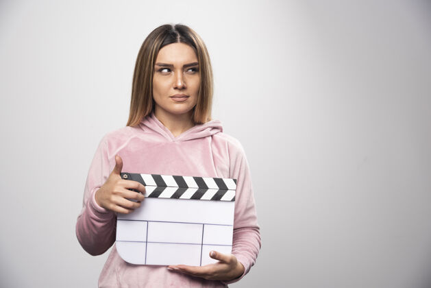 年轻人穿着粉色运动衫的金发女士拿着一块空白的隔板 摆出自然的姿势电影视频员工