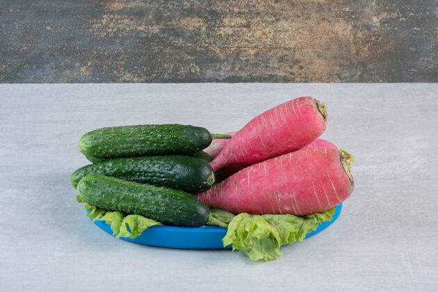 叶健康的黄瓜和红萝卜放在蓝色的盘子里高质量的照片盘子生的蔬菜
