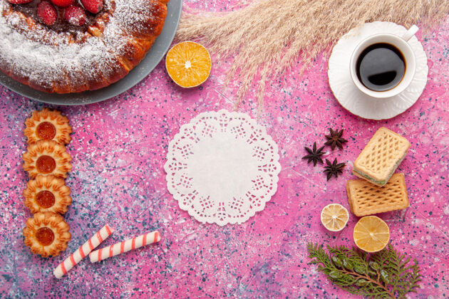 杯子俯瞰美味的草莓蛋糕糖粉蛋糕加华夫饼干和一杯茶放在粉红色的桌子上蛋糕甜甜的糖饼干馅饼蛋糕桌子粉末