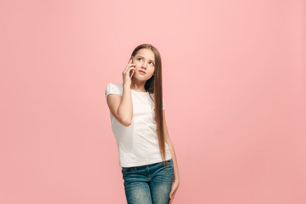 成功快乐的少女站着 微笑着用手机在时尚的粉红色工作室年轻女性健康