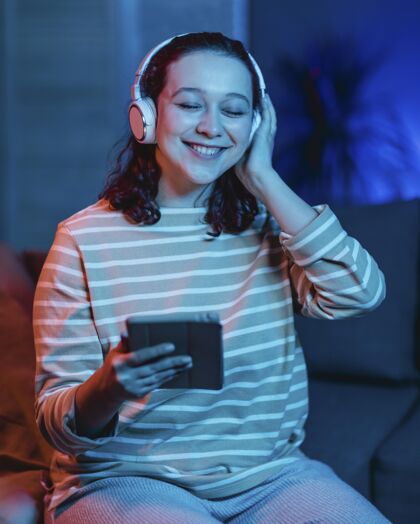 人笑脸女人在家里用耳机和平板电脑科技小玩意耳机