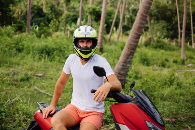 乘坐在热带丛林地带骑着红色摩托车的壮汉运动控制运动