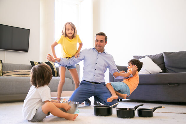 地毯快乐的白种人和孩子们一起玩耍 展示自己的力量快乐的孩子们在客厅的地毯上玩得很开心游戏用的盘子和碗童年 周末和家庭活动的概念碗孩子女儿