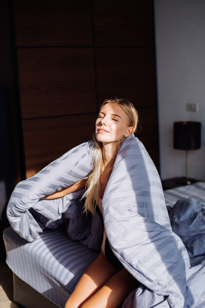 卧室卧室里的快乐平静的女人肖像 穿着灰色的条子毯子和黑米色的身体 在家睡觉穿高兴成人舒适