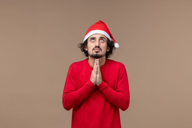 人前视图：年轻人在棕色背景上祈祷圣诞节背景脸情感